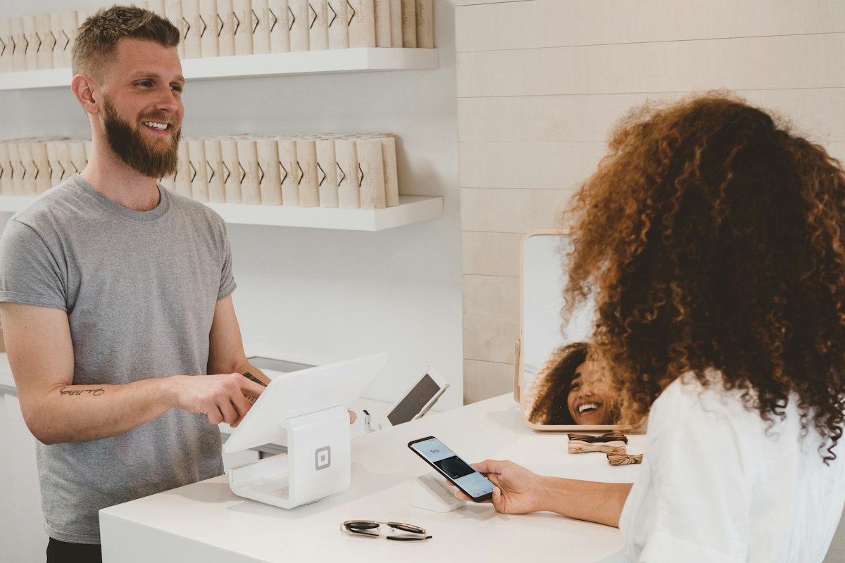 Business owner taking a contactless payment from a smiling customer